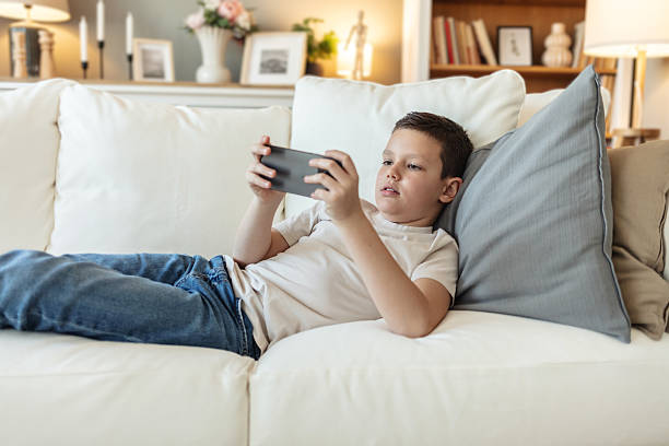 istock Caucasian boy, streaming and smartphone for educational games, growth and development in home. Kid, mobile tech and sports for creativity, fun and social media with application, download and playing. 2226530506