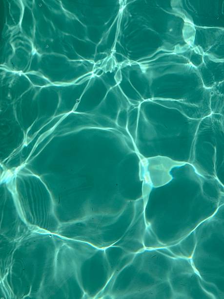 Closeup of clear turquoise water surface in sunlight with natural ripple patterns and shimmering light reflections perfect for summer backgrounds wellness themes and refreshing design visuals Sunlit Turquoise Water Reflection