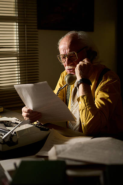 istock Senior Caucasian Man Talking on Landline Phone While Reading Documents Indoors 2226534296