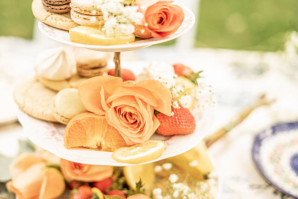 istock tiered dessert stand decorated with assorted macarons, sliced citrus fruit, strawberries, and fresh orange roses, styled for an outdoor garden tea party 2226534744