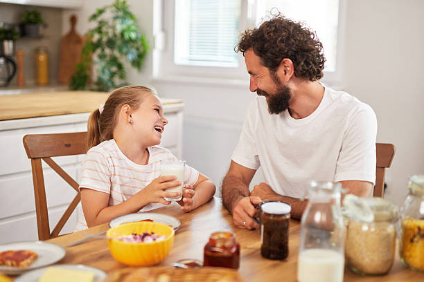 istock Father and daughter laughing and having breakfast together in kitchen 2226536252
