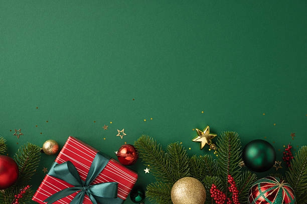 istock Christmas decorations with a wrapped gift box, ornaments, and pine greenery on green background 2226536793