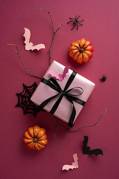 istock Halloween-themed vertical composition featuring a wrapped present with black ribbon, bats, pumpkins, and spiders 2226536859