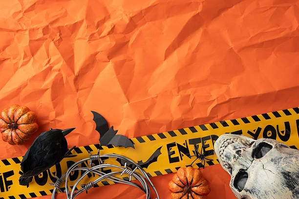 istock Spooky Halloween arrangement featuring a skull, pumpkins, black bird, and caution tape on a vibrant orange backdrop, creating a festive and eerie atmosphere for seasonal celebrations and decorations 2226536868