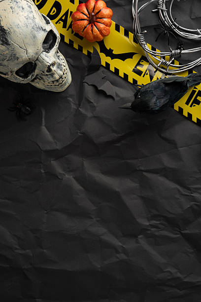 istock Dark vertical Halloween-themed background featuring a skull, mini pumpkin, caution tape, and eerie accessories. 2226536873