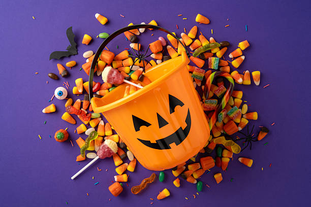 istock Assorted Halloween candies spilling from a jack o'lantern bucket, surrounded by festive decorations including candy corn, lollipops, and spooky elements, representing joyful celebration of Halloween 2226536875