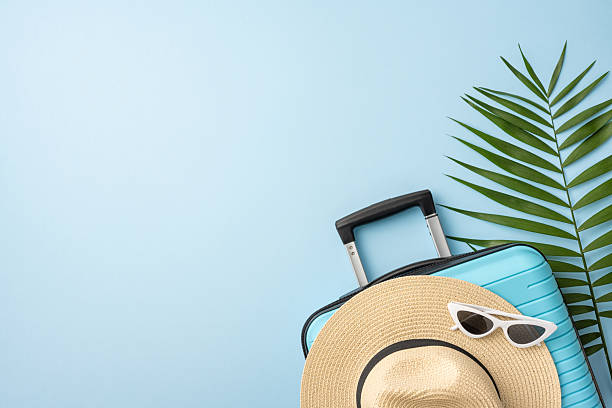 istock Travel essentials arranged, including a suitcase, sunhat, sunglasses, and a tropical green leaf, ideal for summer vacation 2226536877