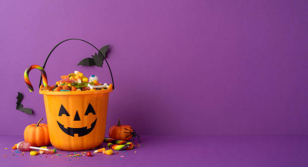 istock Festive Halloween pumpkin bucket with assorted candy and colorful decorations on a side view desk vibrant backdrop 2226536924