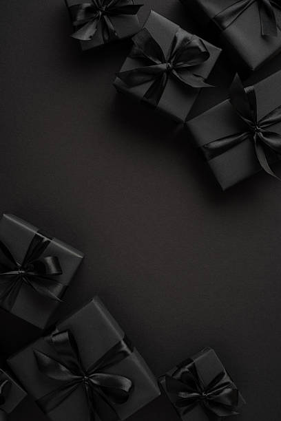istock Black gift boxes with matching ribbons placed on a dark vertical background create a minimalist and modern essence 2226536936