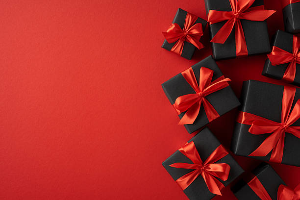 istock Black gift boxes decorated with red satin ribbons arranged on a vibrant red surface to convey feelings of luxury, celebration, and elegance 2226536947