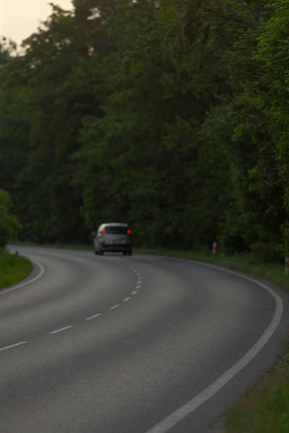 istock A car is currently driving down a winding and curvy road in the woods 2226540864