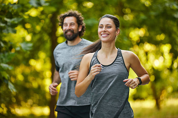 Couple running through forest on summer day