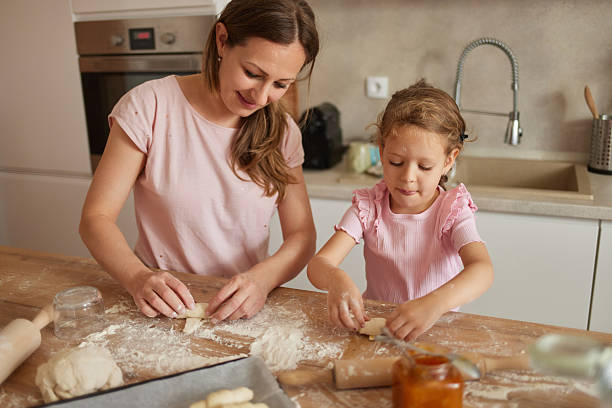 istock Mother and daughter making dough pastry in kitchen 2226543336