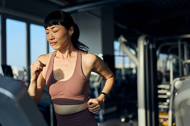 istock Focused Woman Running on a Treadmill in a Spacious Modern Gym 2226543562
