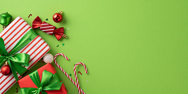 istock Christmas decorations include wrapped presents, candy canes, red bows, and ornaments on a green surface 2226548509