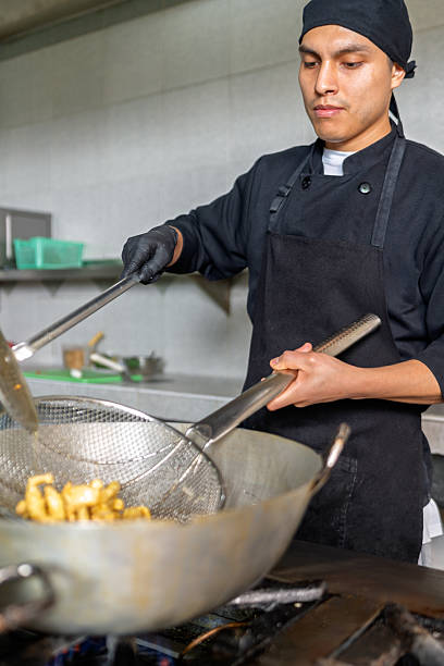istock Peruvian chef frying fish in wok in restaurant kitchen 2226551712