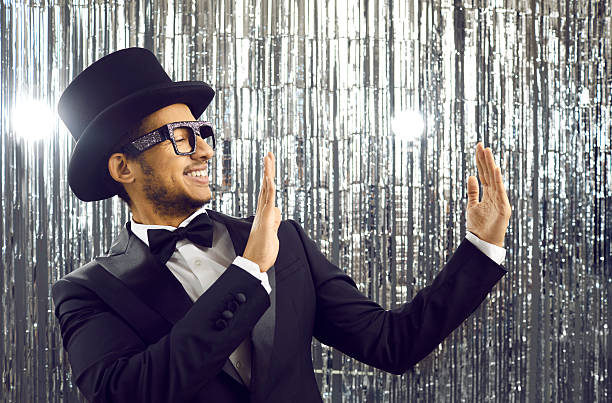 istock Smiling young latin american in black tuxedo holding empty space on shiny silver background. 2226553209