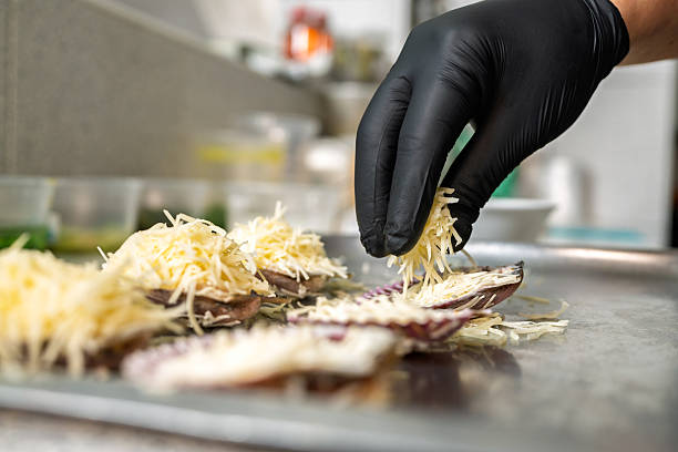 istock Chef adding grated parmesan to scallops au gratin on metal tray 2226553430
