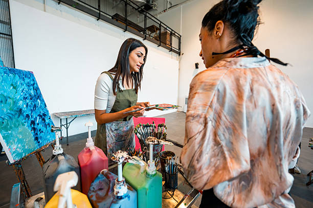 istock Young Women In Gray Apron Teaching Color Mixing Techniques At Bright Art Studio Workshop 2226555664