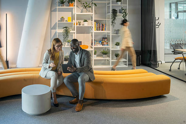 istock Smiling business people using digital tablet in modern office lobby 2226555910