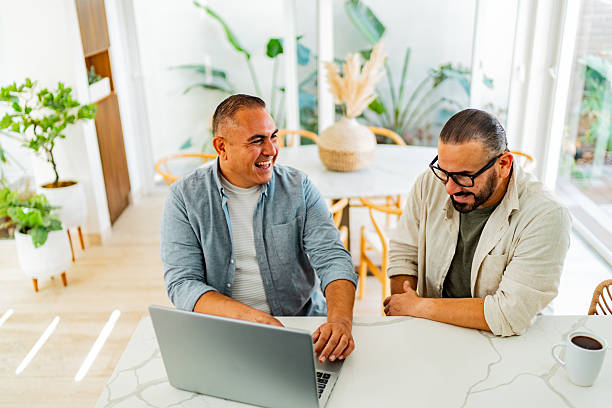 istock Gay couple talking and using laptop at home 2226559521