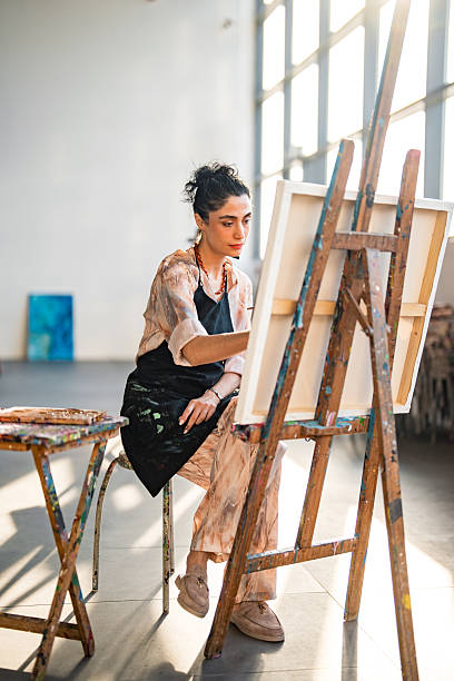 istock Young Middle Eastern Artist In Beige Attire Contemplating Canvas At Sunlit Studio 2226561340
