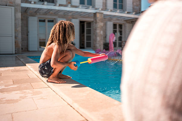 istock Mixed Race Boy with Squirt Gun by the Pool 2226563817