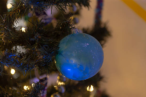 A beautiful blue ornament is elegantly hanging from a festive christmas tree, adding a touch of color and joy to the holiday season