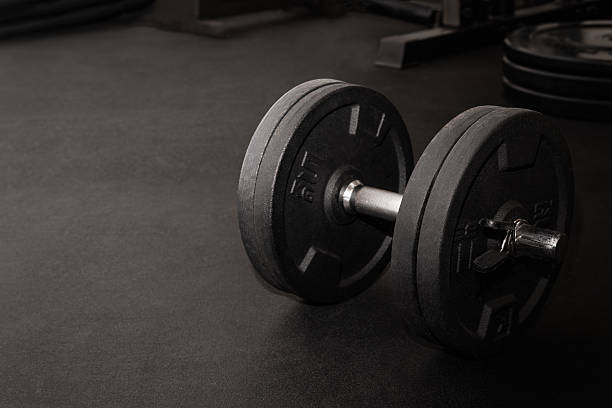 istock Black dumbbell resting on gym floor after intense workout 2226567489