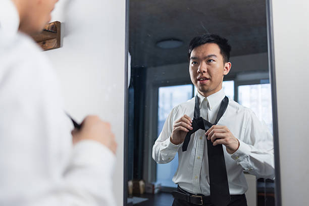 istock Young man confidently tying his tie in the mirror before work 2226573199