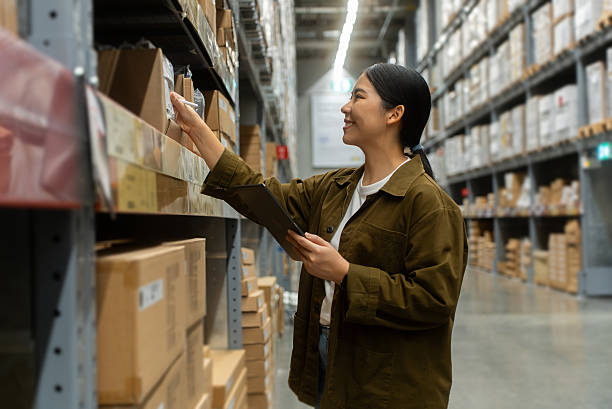 istock Portrait smiling woman worker checking real-time stock inventory to fulfill data using smart digital tablet in logistics center with stacked shipping boxes and supply chain products in warehouse. 2226575392