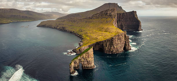 Faroe Islands Drangarnir Sea Stack Natural Arch and Vagar Island Aerial Drone XXL Panorama. View of Drangarnir Sea Stack and Vagar island near Sørvágur village. Drangarnir is located between the Islet Tindholmur and Vágar Island. Vágar Island. Faore Islands, Denmark, Northern Europe, Nordic Countries
