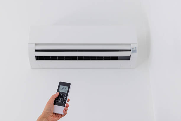istock Air conditioner temperature adjustment with remote controller in room at home. Woman's Hand Using Air Conditioner Remote Control At Home 2226585717