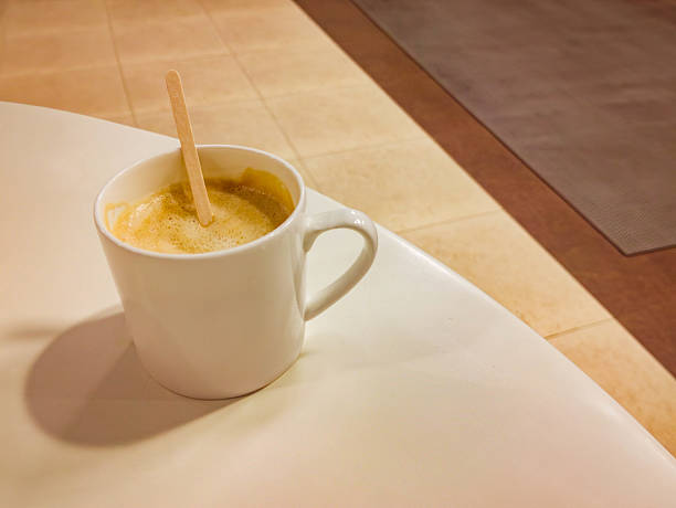 A single cup of cappuccino sits on a white table in Bengaluru, India, creating a minimalist composition.