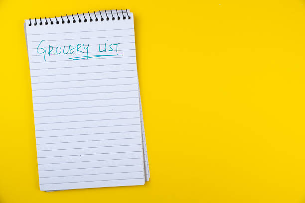 istock Spiral notebook with blank pages and 'grocery list' handwritten on cover placed on vibrant yellow background for organization and shopping planning purposes 2226594530