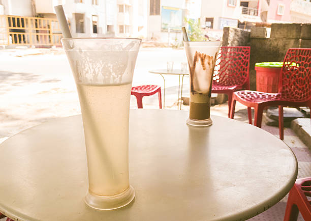 Two iced drinks on a cafe table outdoors in Bengaluru, India.  Shallow depth of field, sunlit setting.