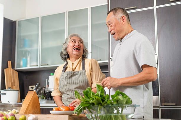 istock Happy Senior Asian Couple Laughing While Cooking in Kitchen, Joyful Elderly Spouses Enjoying Time Together Preparing Food, Smiling Mature Couple Shares a Moment in a Modern Kitchen 2226595643