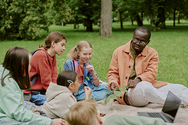 istock School Teacher Guiding Children Learning Outdoors in Park Setting 2226596669