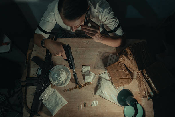 Scene depicting an individual working with illicit materials under low light conditions. The environment conveys themes of crime and clandestine activities.
