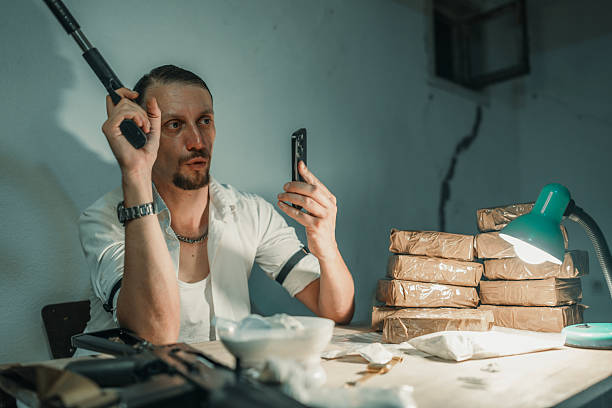 istock Man Using Phone Near Bundled Items and Illuminated Lamp in Dimly Lit Room 2226601460