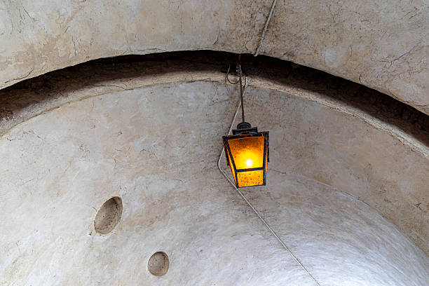 A ceiling lighting lamp in metal retro design was installed at the rock mine industrial workplace, it glowing in orange warm light shade.