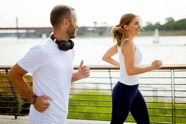 istock Energetic couple jogging along a riverside pathway on a sunny day, sharing smiles and motivation during their workout 2226602952