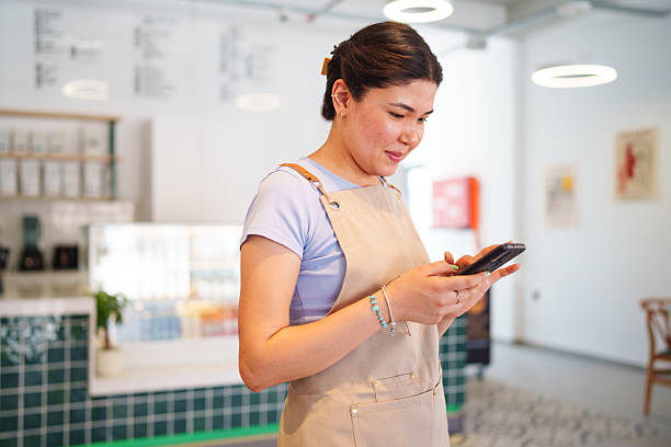 istock Young Female Cafe Employee Using Mobile Phone 2226606850