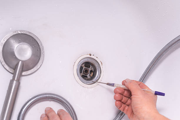 istock Bathroom maintenance in progress as person removes blockage from drain using tool. Manual removal of clog from bathtub drain.elimination of blockage in the sink when draining water manually using tool 2226608365
