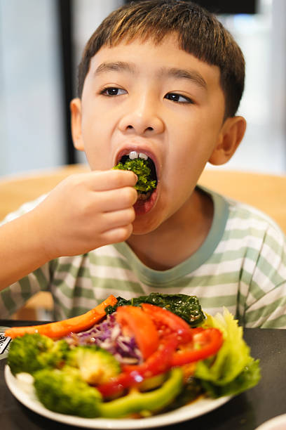 istock Boy enjoy eating vegetable salad on the table 2226608841