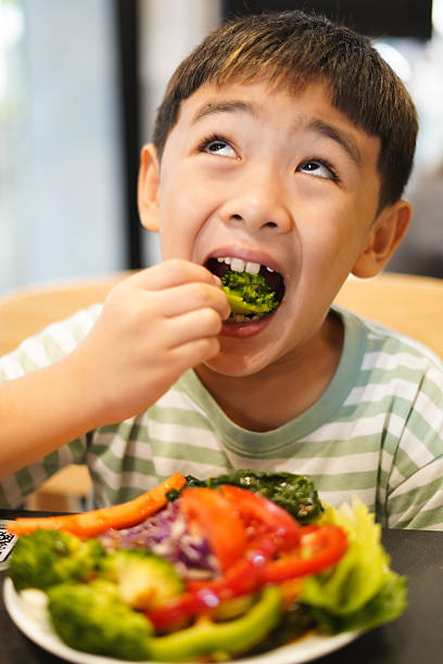 istock Boy enjoy eating vegetable salad on the table 2226608860
