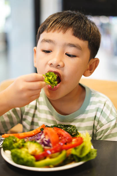 istock Boy enjoy eating vegetable salad on the table 2226608877