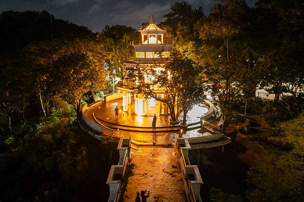 Illuminated Khao Rang Viewpoint in Phuket at night, a beautiful architectural landmark amidst lush tropical trees.