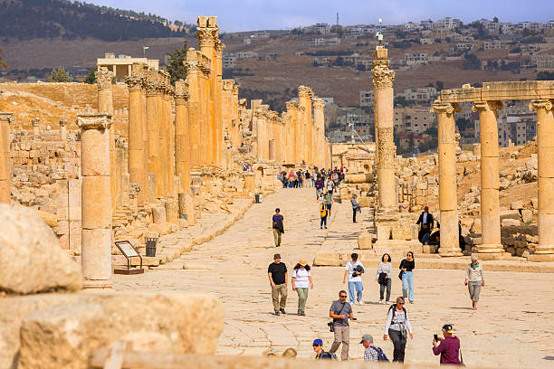 Jerash, Jordan - November 7, 2022: People on square with row of Corinthian columns of Oval Forum Plaza and Cardo Maximus, high angle view