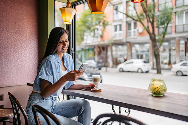 istock Young Woman Drinking Coffee While Using Her Phone In A Coffee Shop 2226614434
